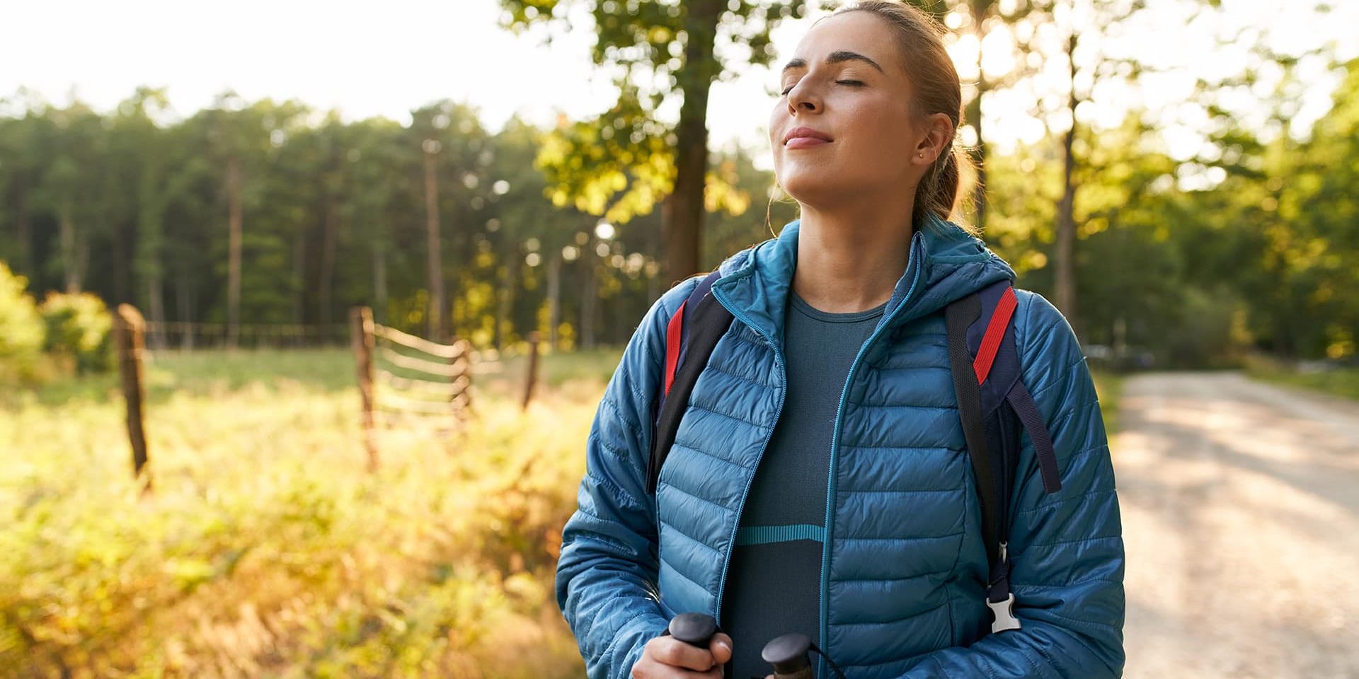 Adult woman relaxing in forest taking big breath enjoying sunny summer countryside walk countryside