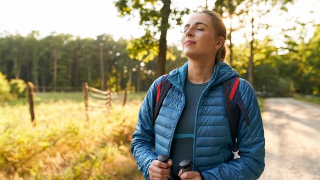 Adult woman relaxing in forest taking big breath enjoying sunny summer countryside walk countryside Letar du efter olika sätt att främja ditt välbefinnande och din hälsa? Ny digital välmåendeguide hjälper dig